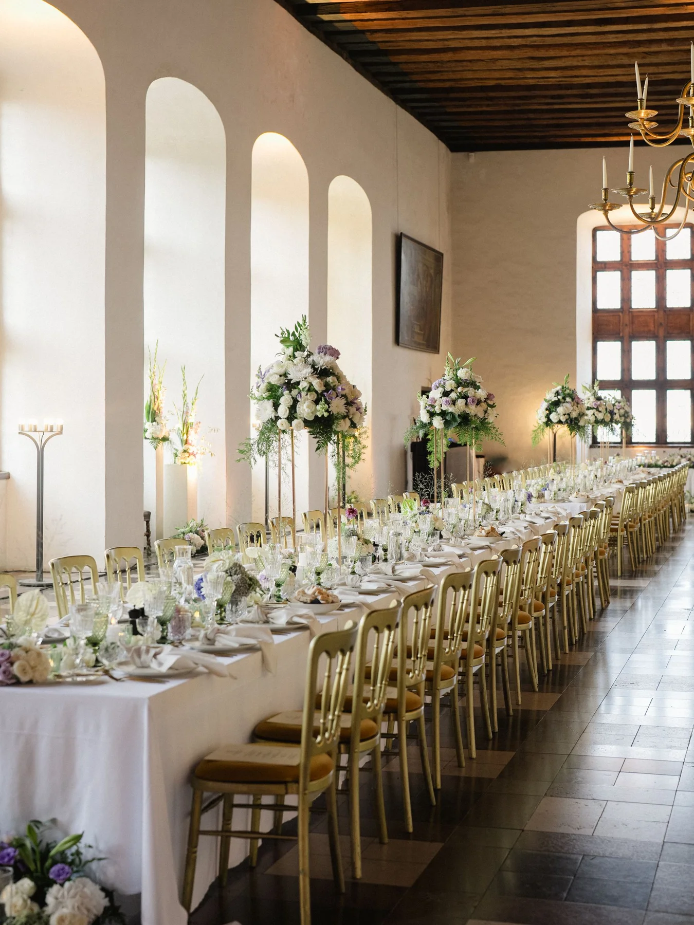 Langt festdækket bord med blomster i en historisk sal på Kronborg